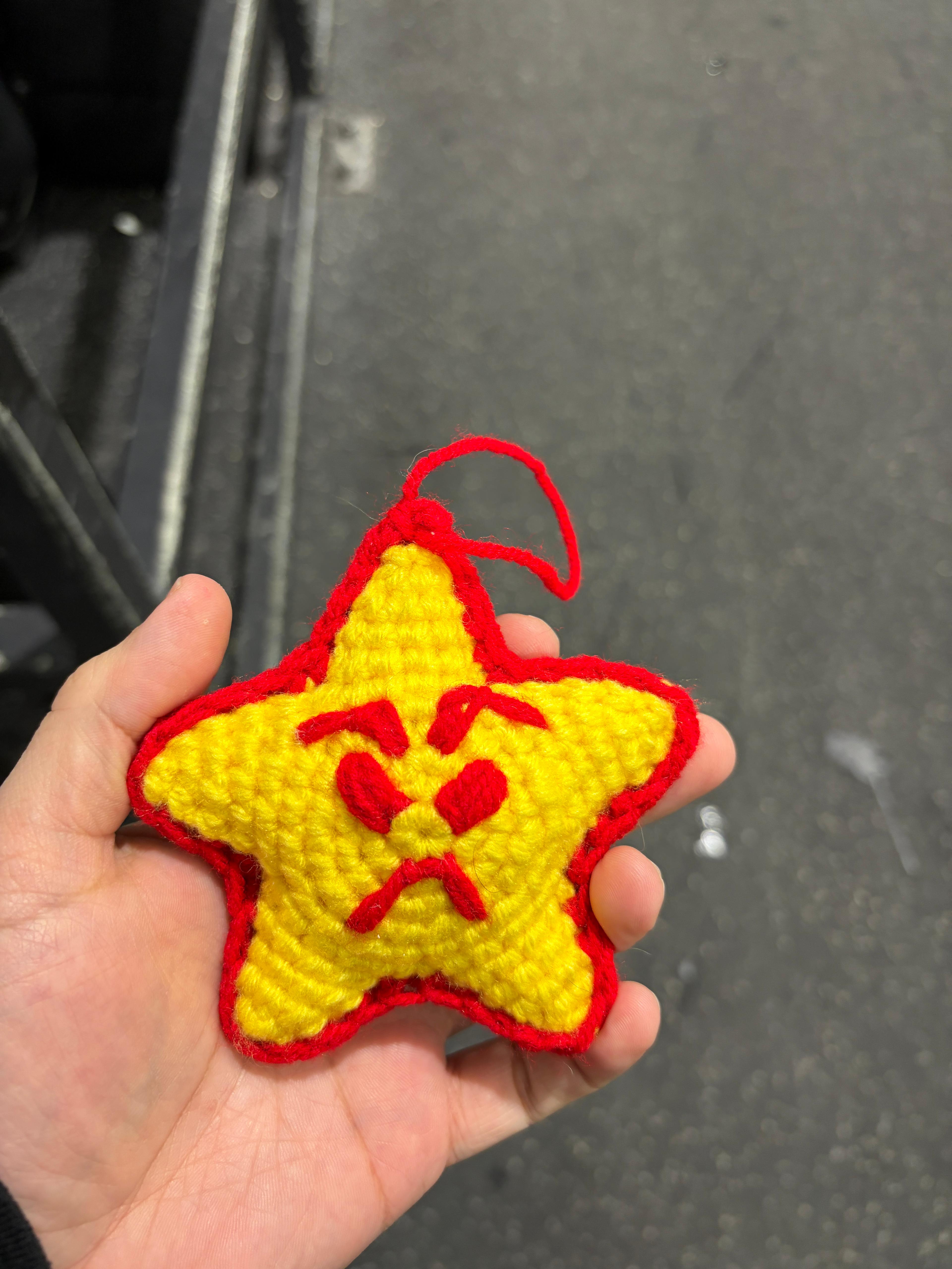 Junior, the crochet star mascot, held in someone's hand